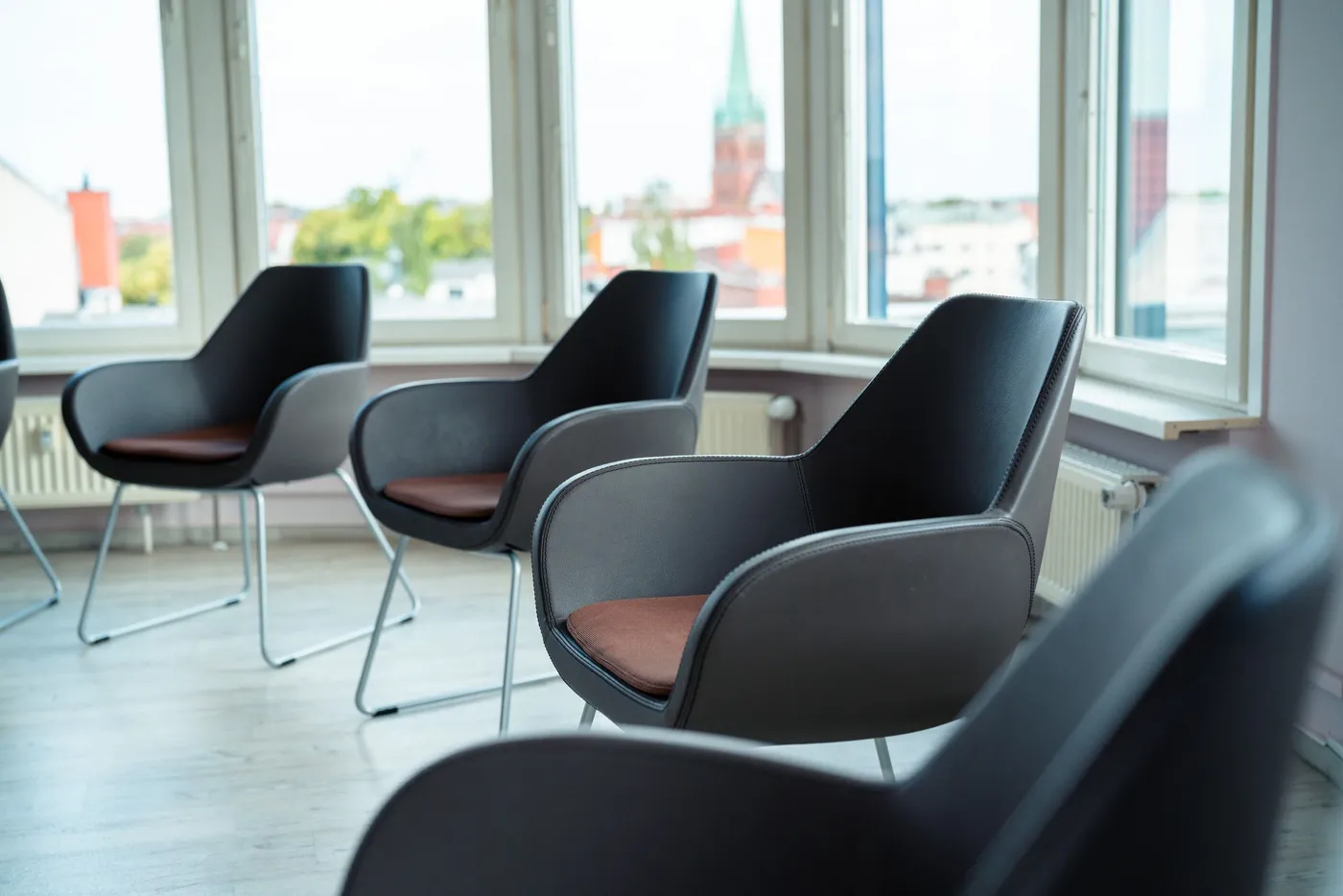 Moderne Stühle in einem hellen Raum mit großen Fenstern und Stadtblick.