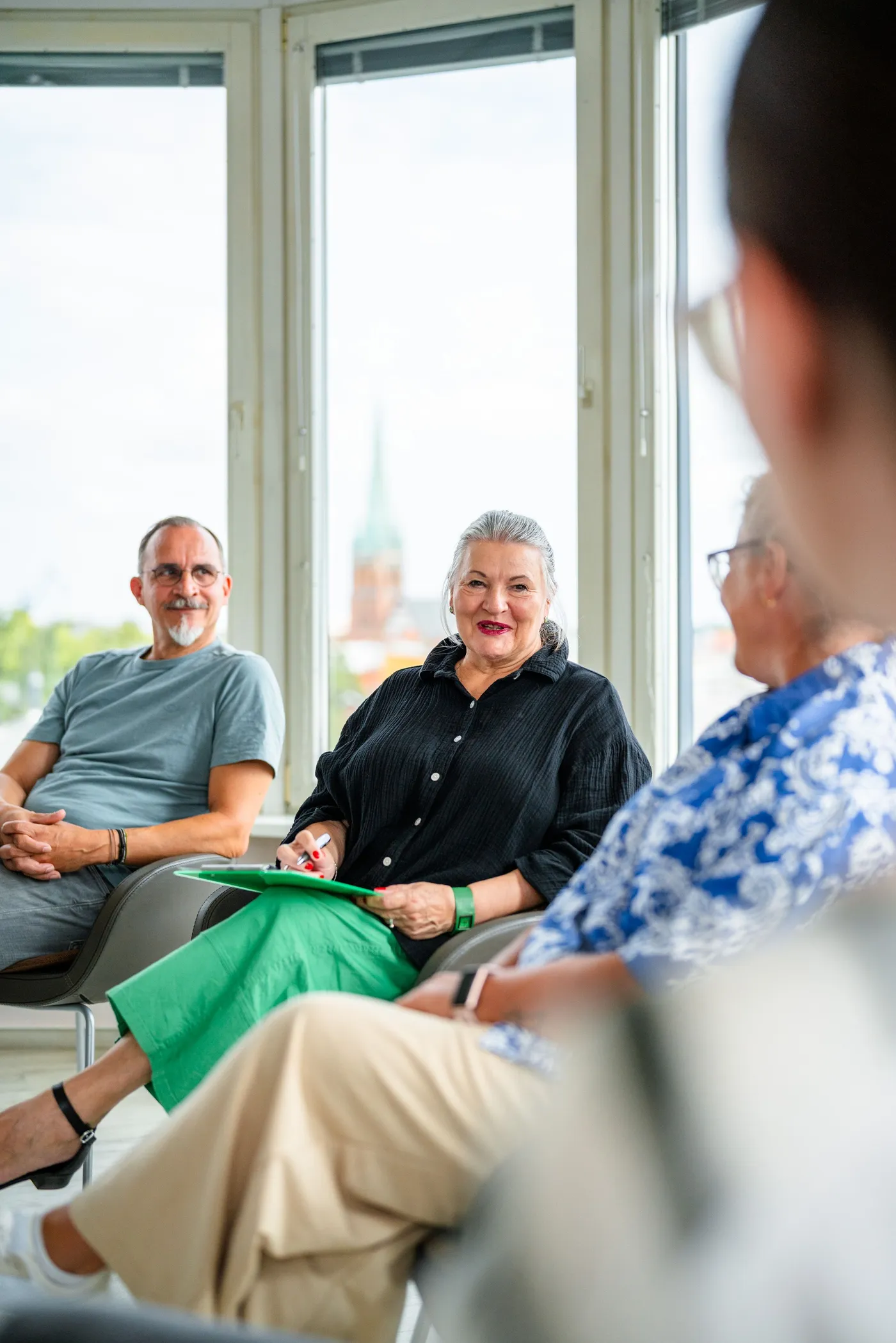 Eine Gruppe von Menschen sitzt in einem hellen Raum und diskutiert.