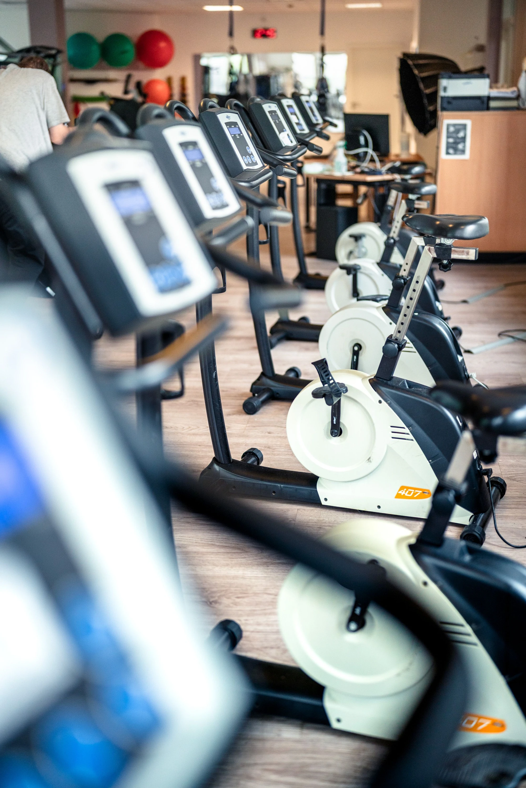 Reihe von Fitnessgeräten in einem modernen Trainingsraum mit verschiedenen Sportgeräten im Hintergrund.