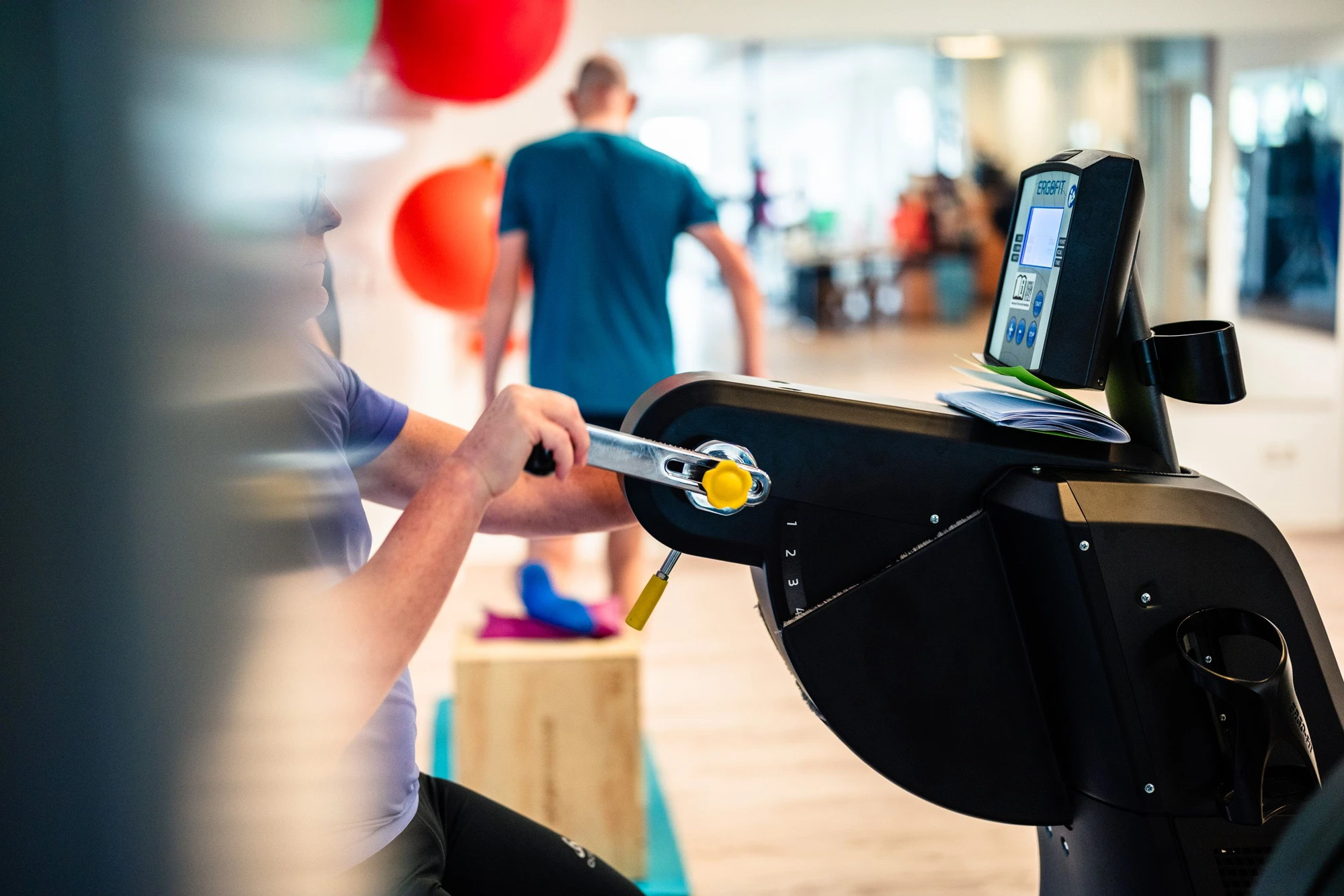 Eine Person trainiert an einem Fitnessgerät in einem modernen Trainingsraum.