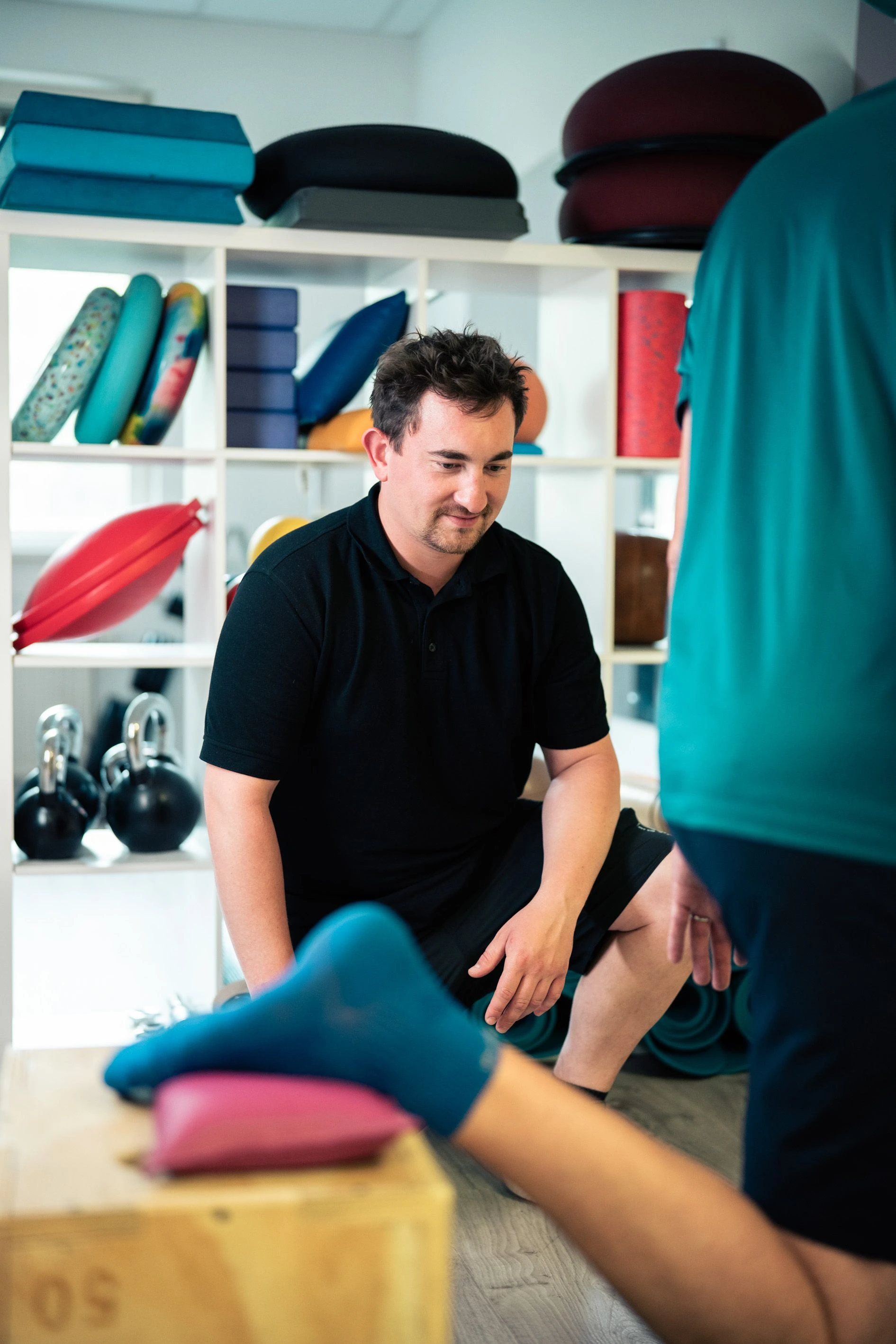 Ein Mann beobachtet aufmerksam eine Übung mit einem Fuß auf einer Trainingsunterlage.