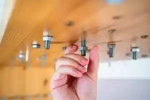 Eine Hand greift nach einer Schraube unter einem Holzregal.